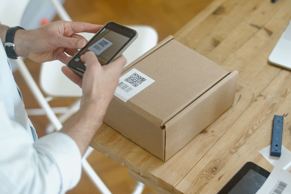 A person holding a smartphone over a QR code on a package